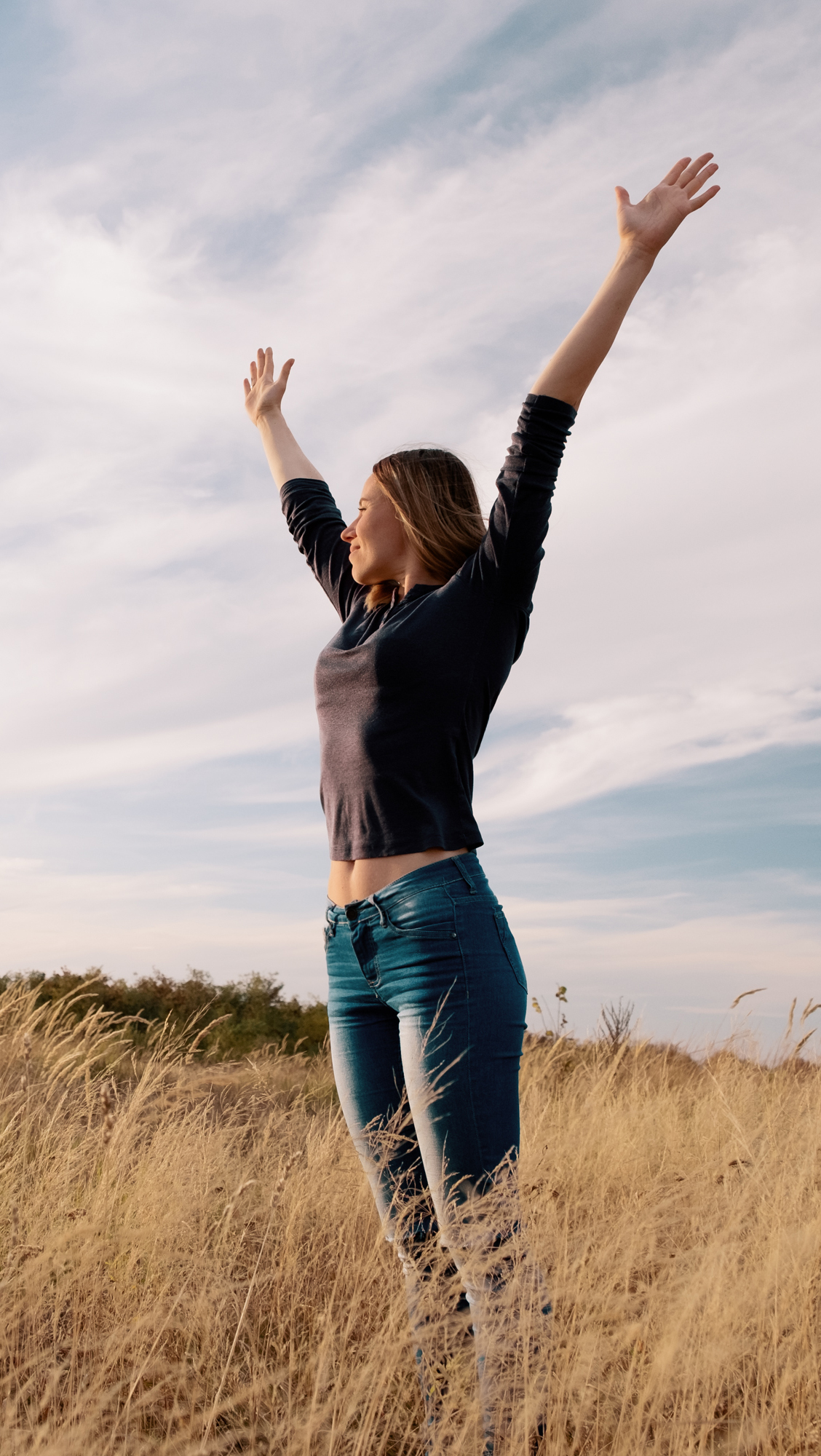 Young happy woman in a golden field on sunset.